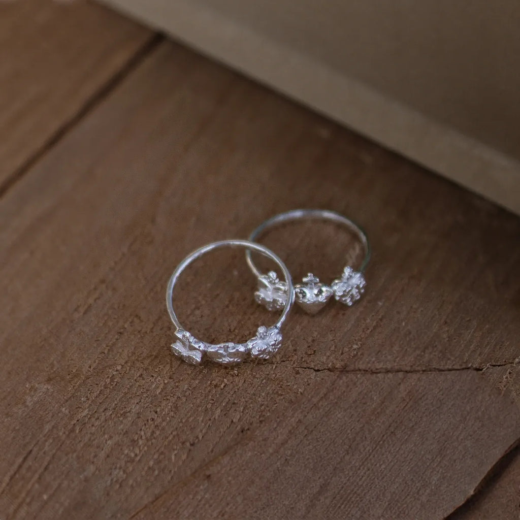 anillos plata tres corazones sagrados sobre textura madeara