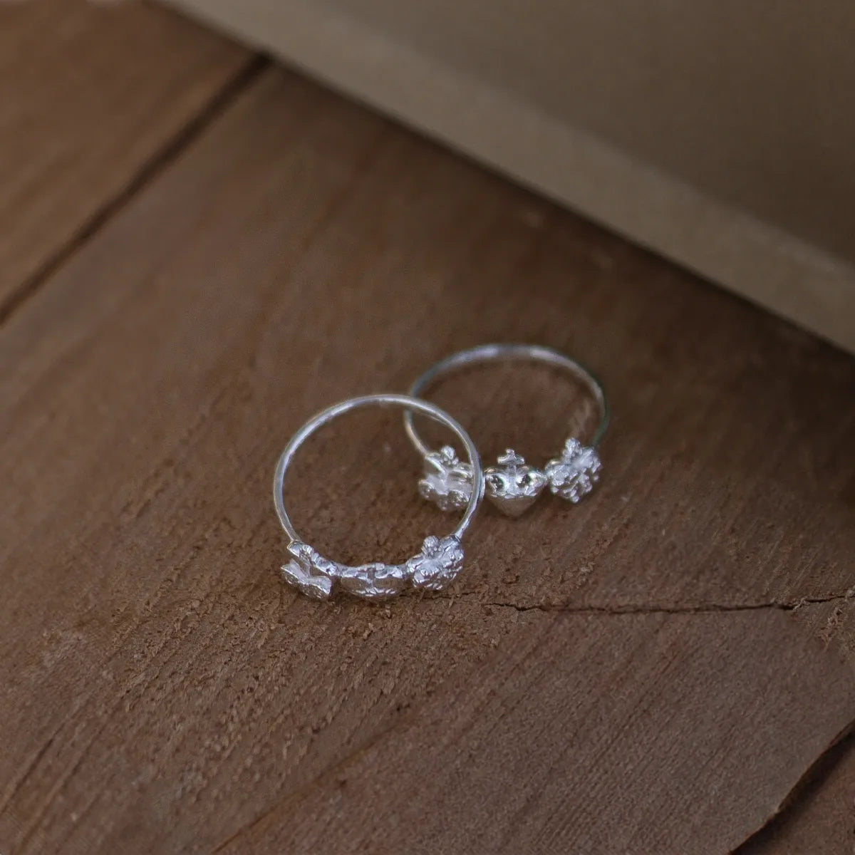anillos plata tres corazones sagrados sobre textura madeara