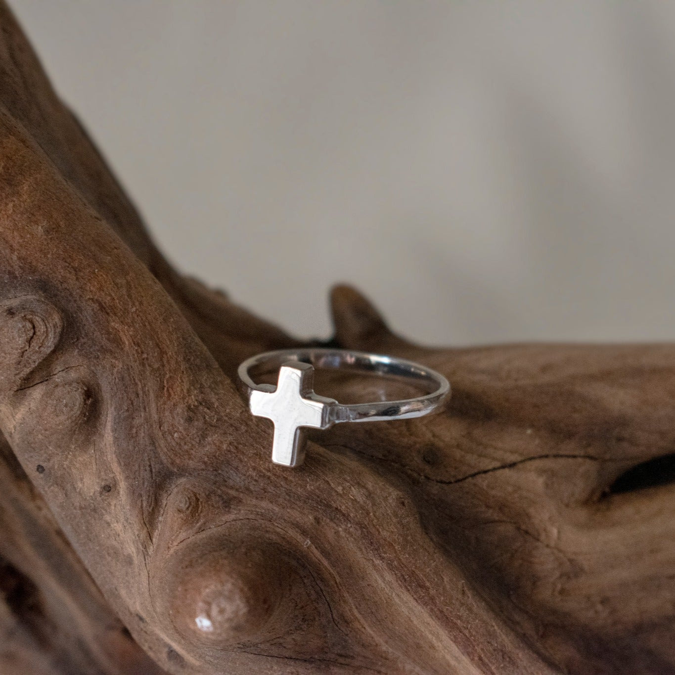 anillo plata forma de cruz sobre textura madera