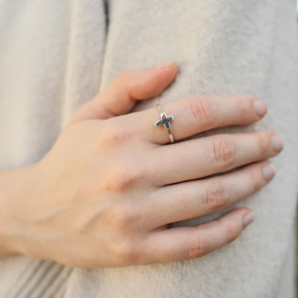 anillo de plata cruz, mano delicada