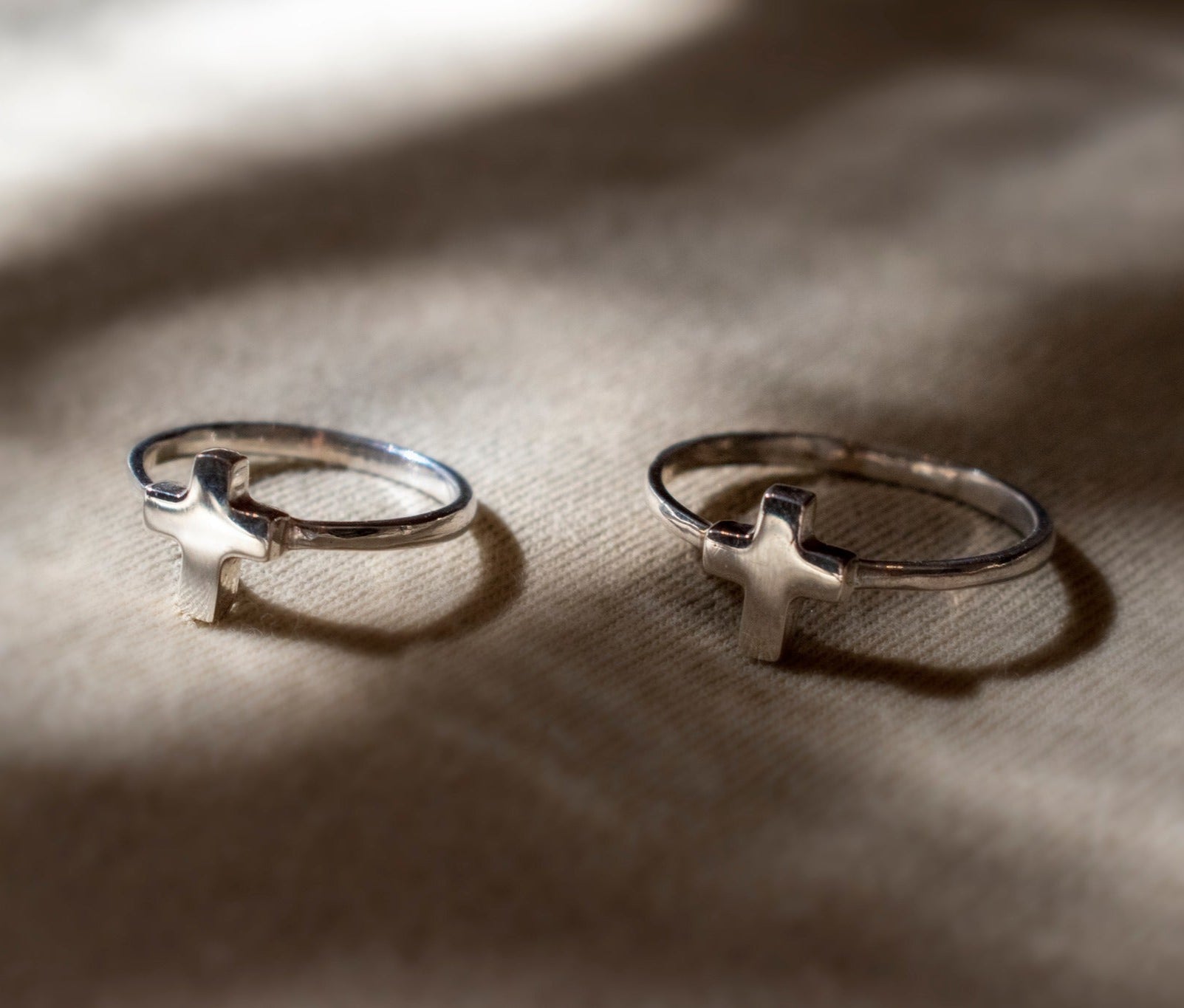 anillos de plata en forma de cruz sobre fondo liso